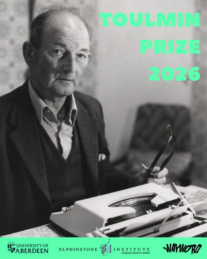 Mature gentleman, thining on top, sitting in front of a portable typewriter.